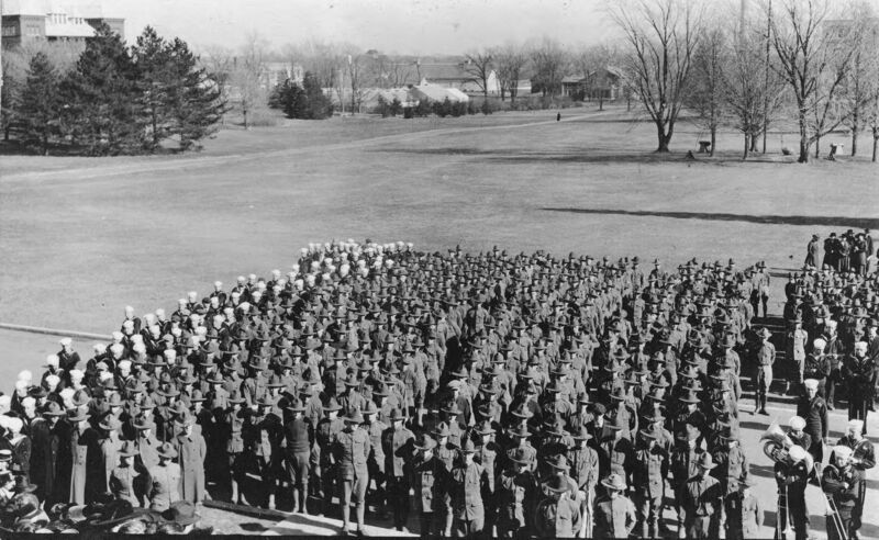 Military members standing at attention with military band members on the right. 