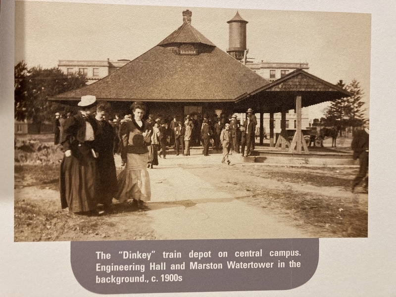 The "Dinkey" train depot on central campus. Engineering Hall and Marston Watertower in the background. , c. 1900s