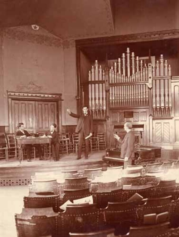 Four men speaking in front of the organ at Morrill Hall 