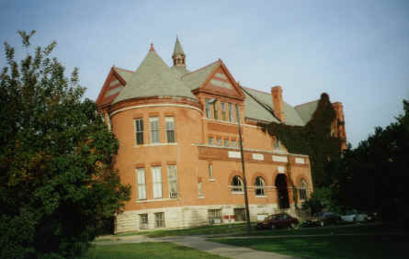 Color image of Morrill Hall from the south-east. Cars are parked along the street in front of the entrance.