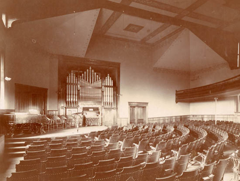 View of Morrill Hall Chapel seen from the back row facing towards the stage and pipe organ.